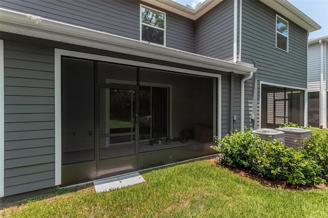 back of property featuring cooling unit, a lawn, and a sunroom