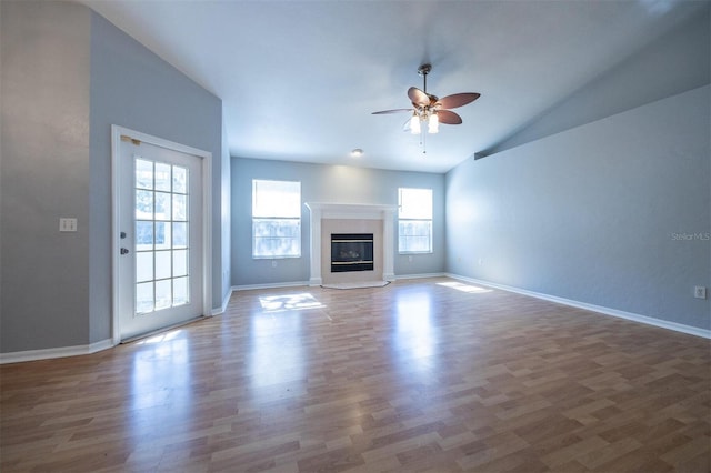 unfurnished living room with a tile fireplace, ceiling fan, lofted ceiling, and hardwood / wood-style flooring