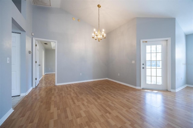 unfurnished room featuring high vaulted ceiling, light hardwood / wood-style floors, and an inviting chandelier