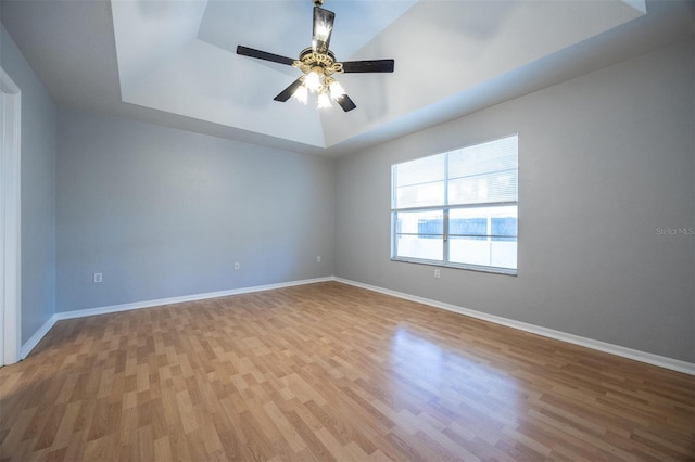 unfurnished room with wood-type flooring, a raised ceiling, and ceiling fan