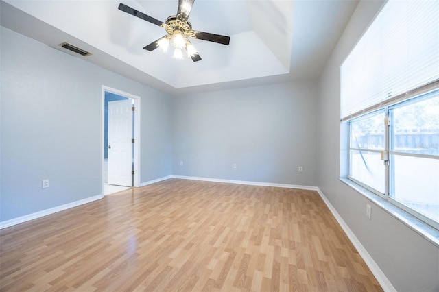 empty room featuring ceiling fan, a raised ceiling, and light hardwood / wood-style flooring