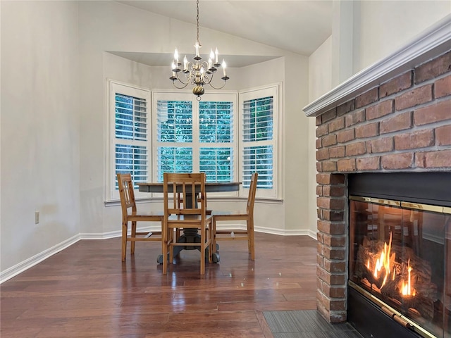 dining space with dark hardwood / wood-style flooring, lofted ceiling, a fireplace, and a chandelier