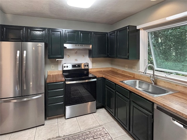 kitchen featuring butcher block countertops, light tile patterned floors, sink, and appliances with stainless steel finishes