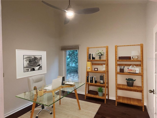 home office with ceiling fan, dark hardwood / wood-style flooring, and a towering ceiling