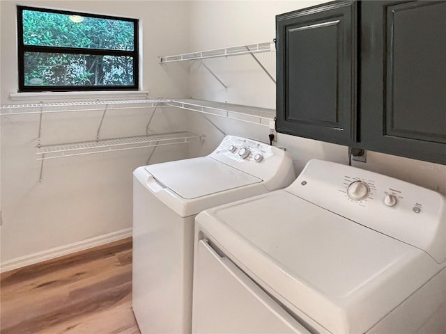 washroom with cabinets, light wood-type flooring, and washing machine and dryer