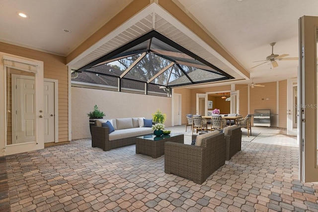 view of patio with an outdoor living space, ceiling fan, and glass enclosure