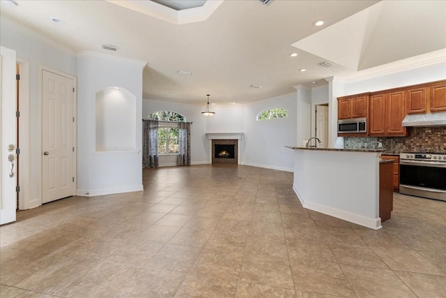 kitchen featuring stone countertops, backsplash, a kitchen island with sink, stainless steel appliances, and crown molding