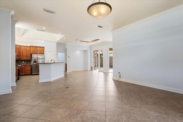 unfurnished living room with ornamental molding, a tray ceiling, and light tile patterned floors