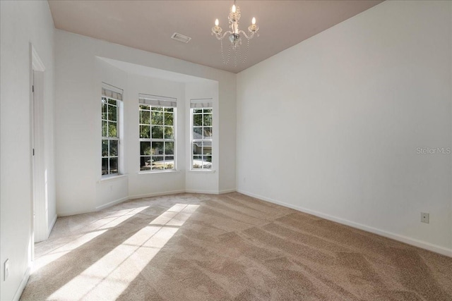 empty room featuring light carpet and an inviting chandelier