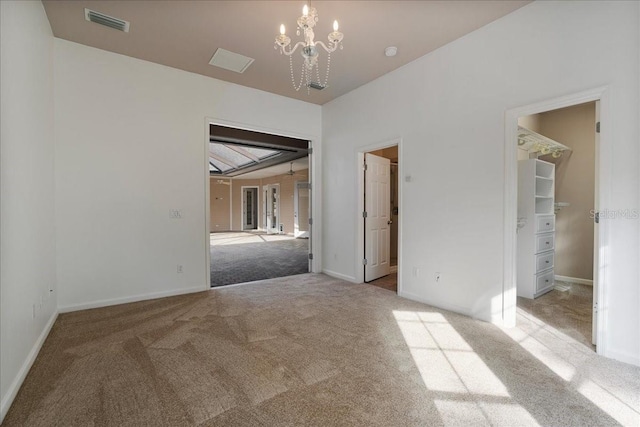 unfurnished room featuring a chandelier and carpet