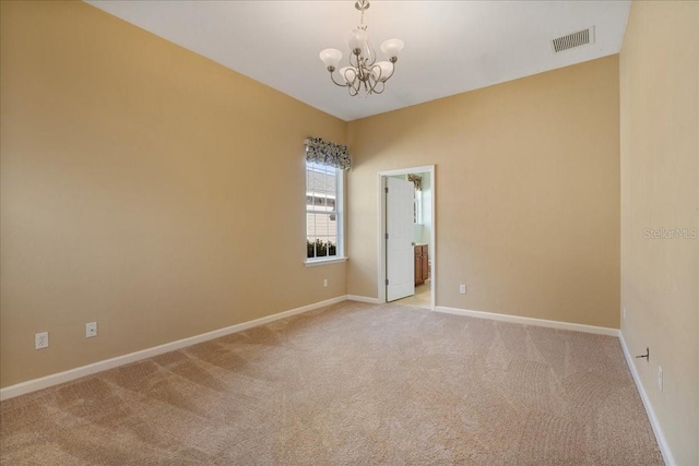 spare room featuring an inviting chandelier and light colored carpet