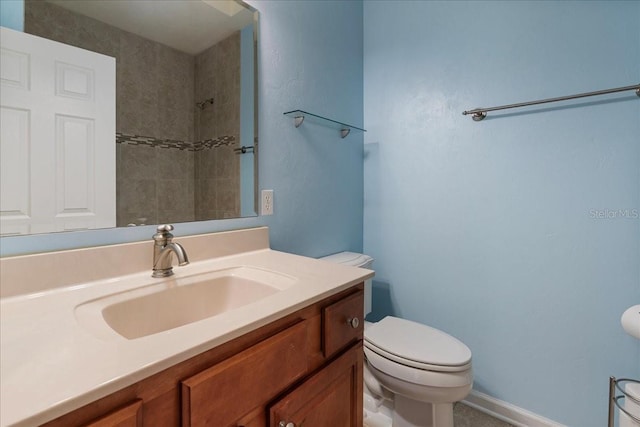 bathroom featuring vanity, tiled shower, and toilet