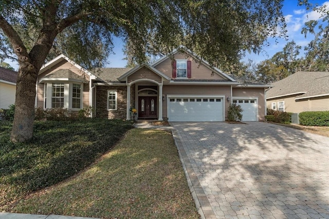 craftsman inspired home with a garage and a front lawn