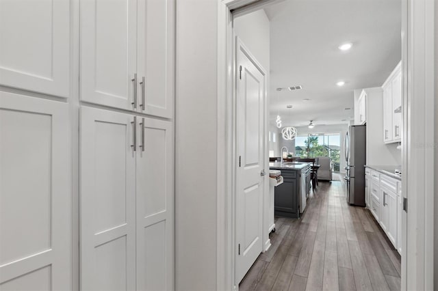 corridor with light hardwood / wood-style floors and sink