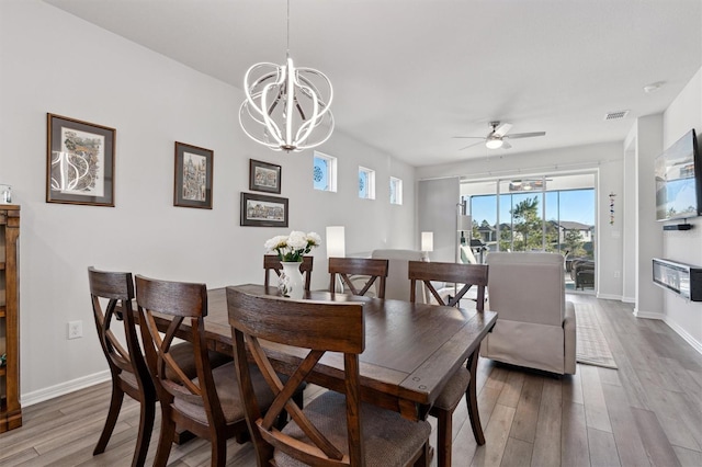 dining space with ceiling fan with notable chandelier and hardwood / wood-style flooring