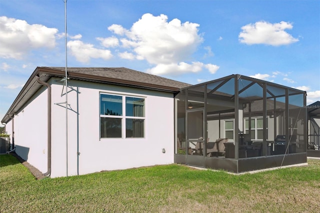 back of property with a lanai, central AC, and a lawn