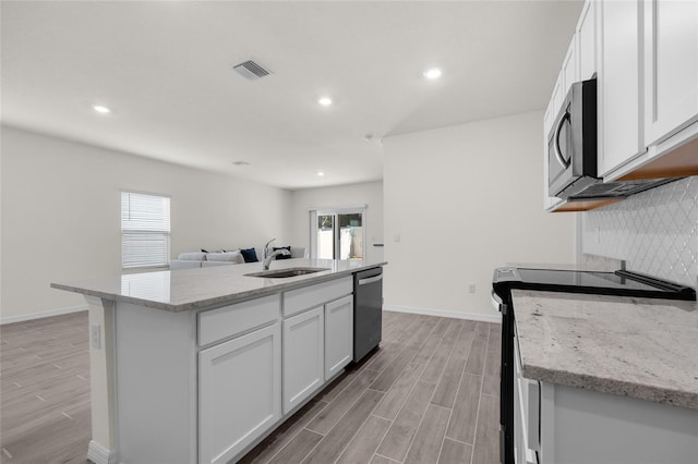 kitchen featuring stainless steel appliances, sink, white cabinetry, an island with sink, and light stone countertops