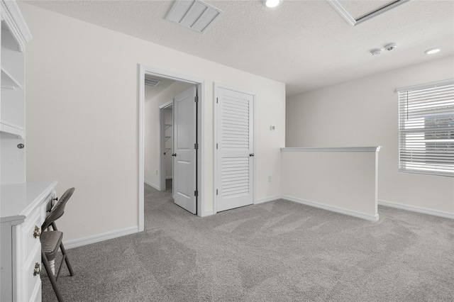 unfurnished office featuring a textured ceiling and light carpet