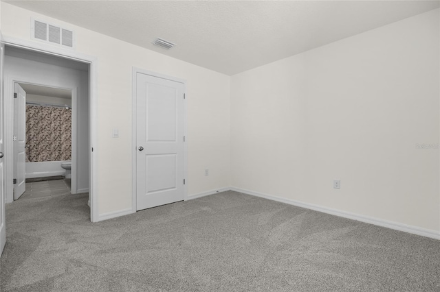 unfurnished bedroom with ensuite bath and light carpet