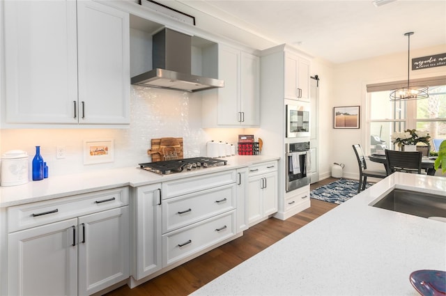 kitchen featuring appliances with stainless steel finishes, dark hardwood / wood-style floors, tasteful backsplash, white cabinets, and wall chimney exhaust hood