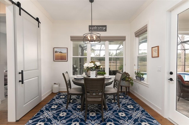 dining room featuring dark hardwood / wood-style floors, a barn door, a chandelier, and crown molding