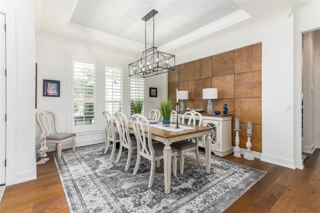 dining area featuring a notable chandelier, dark hardwood / wood-style flooring, and a tray ceiling