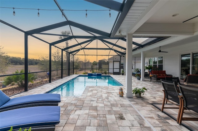 pool at dusk featuring an outdoor living space, a patio, a lanai, and ceiling fan