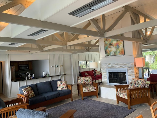 living room with sink, vaulted ceiling with beams, light tile patterned floors, and a fireplace