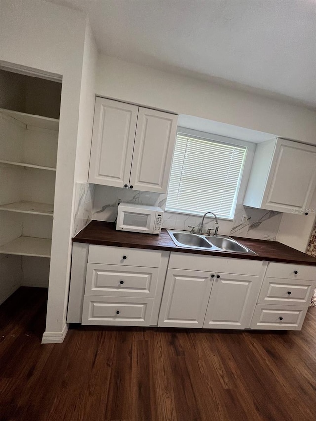 kitchen featuring dark hardwood / wood-style flooring, decorative backsplash, sink, and white cabinets