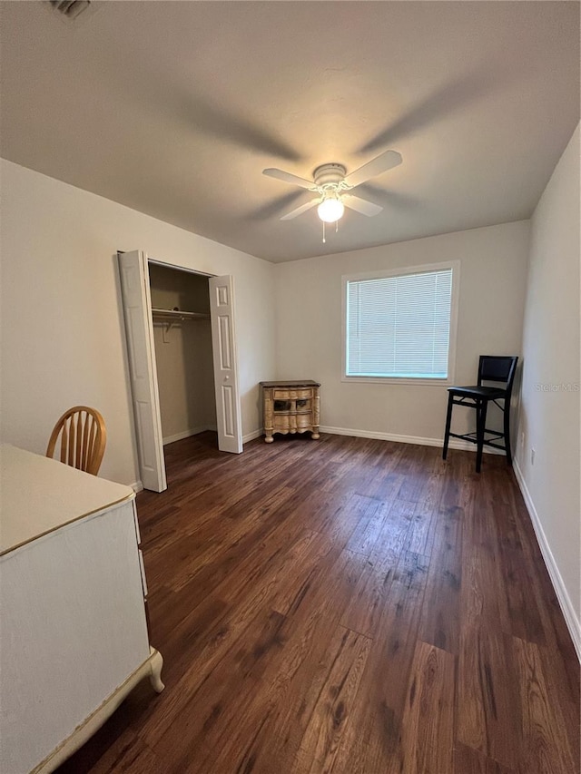 unfurnished bedroom with ceiling fan, a closet, and dark wood-type flooring