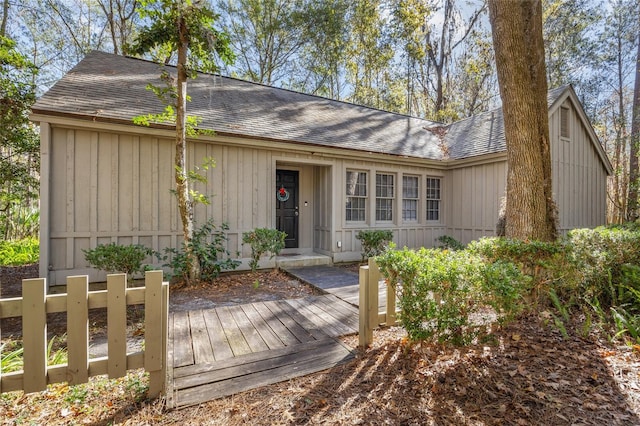 view of front of home with a deck, roof with shingles, and board and batten siding