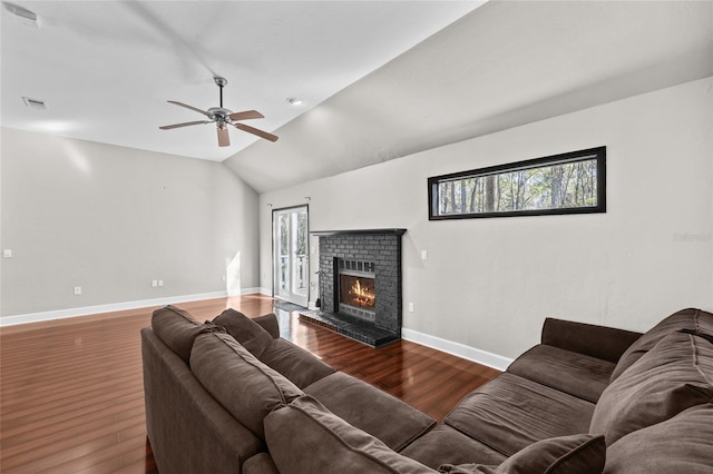 living room with visible vents, baseboards, lofted ceiling, wood finished floors, and a brick fireplace