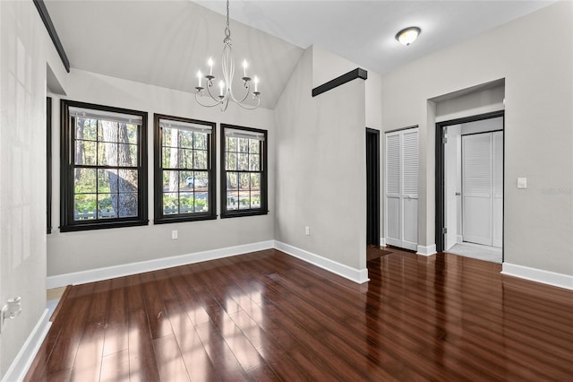 interior space featuring lofted ceiling, a chandelier, dark wood finished floors, and baseboards