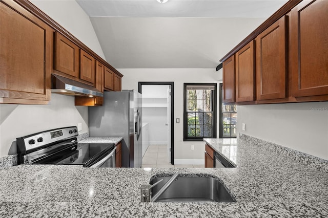 kitchen with under cabinet range hood, appliances with stainless steel finishes, brown cabinets, and light stone counters