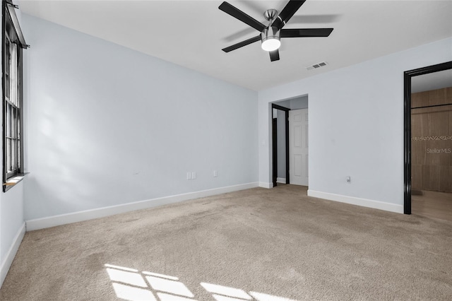 unfurnished bedroom featuring baseboards, visible vents, ceiling fan, and light colored carpet