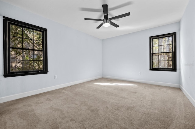 empty room featuring baseboards, ceiling fan, and light colored carpet