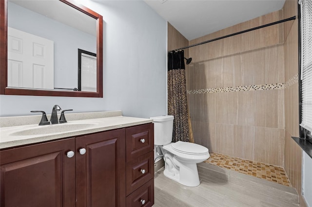 bathroom with toilet, tiled shower, and vanity