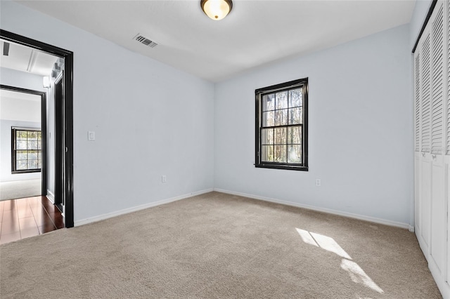 unfurnished bedroom with a closet, carpet, visible vents, and baseboards