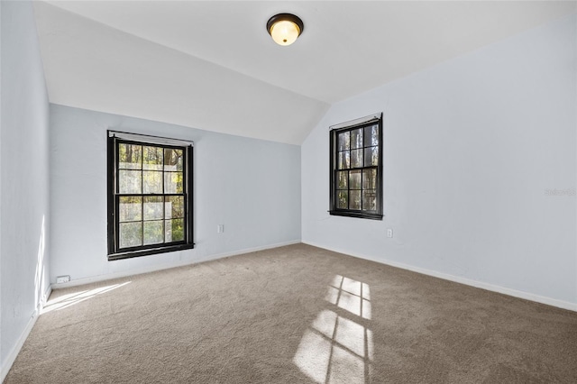 carpeted empty room featuring lofted ceiling and baseboards