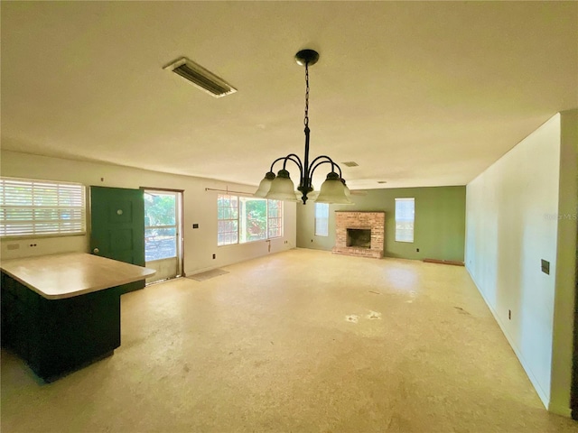 unfurnished living room with a stone fireplace and a chandelier