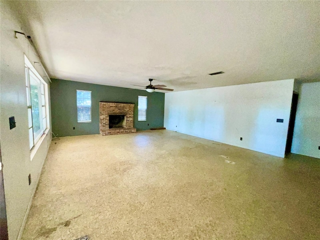 unfurnished living room with ceiling fan and a brick fireplace