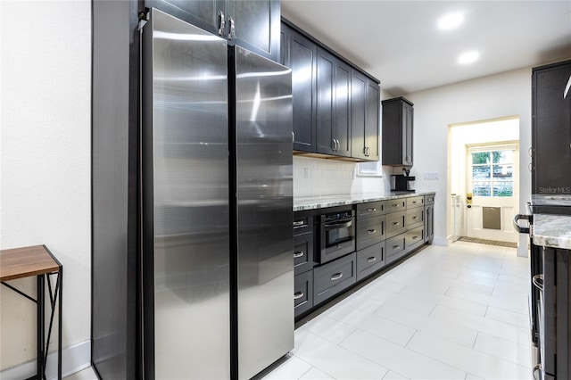 kitchen featuring decorative backsplash, light stone counters, and appliances with stainless steel finishes