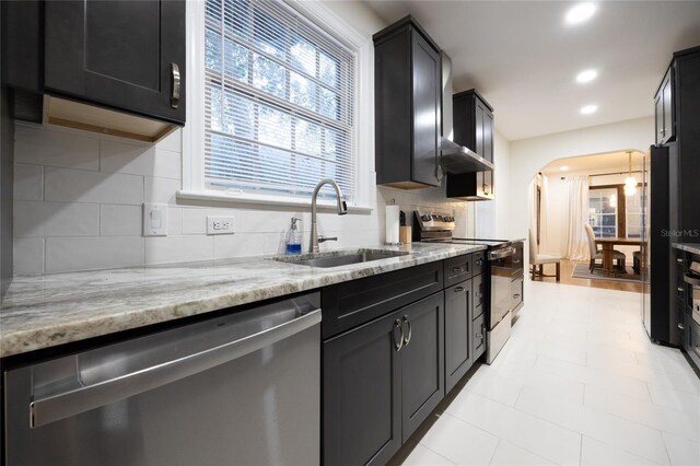 kitchen with decorative backsplash, sink, light stone counters, and appliances with stainless steel finishes