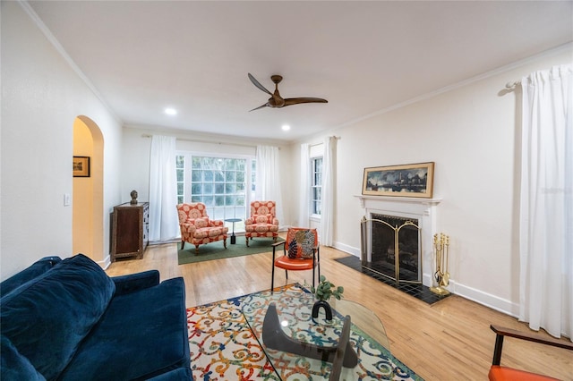 living room featuring light wood-type flooring, ceiling fan, and ornamental molding