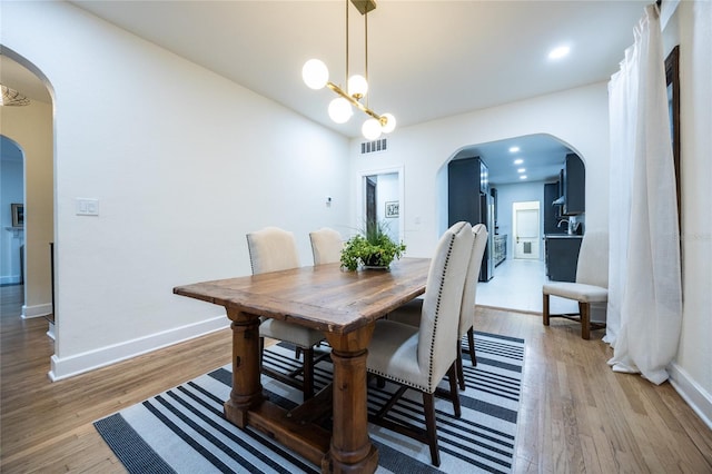 dining space with light wood-type flooring and an inviting chandelier