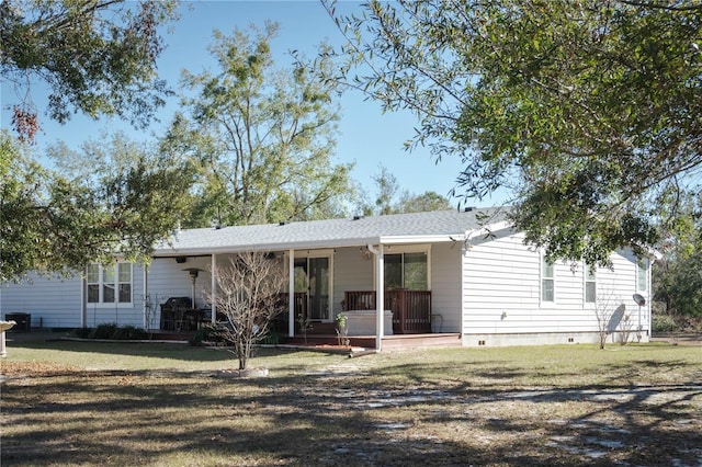 rear view of house with covered porch and a lawn