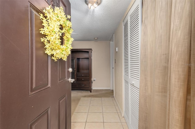 hallway with light carpet and a textured ceiling