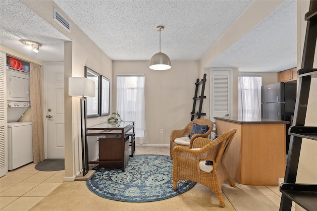 interior space with stacked washer / dryer, a textured ceiling, and light tile patterned floors