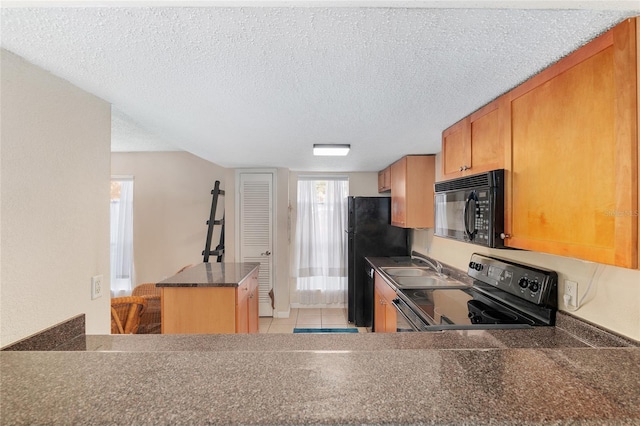 kitchen with light tile patterned flooring, kitchen peninsula, a textured ceiling, and black appliances