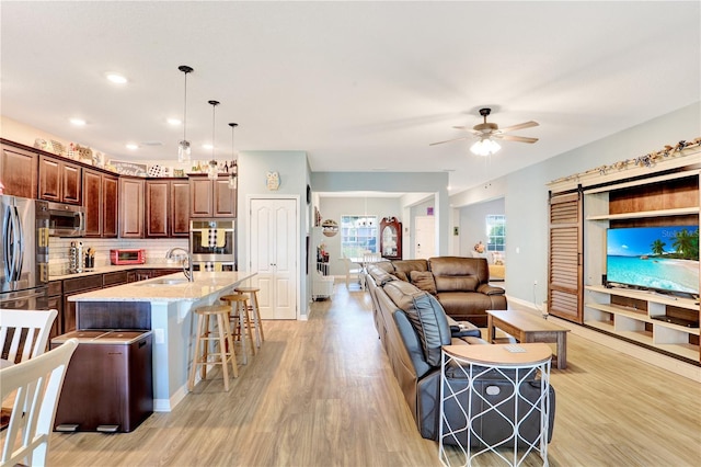 kitchen featuring appliances with stainless steel finishes, a kitchen breakfast bar, sink, decorative light fixtures, and a center island with sink